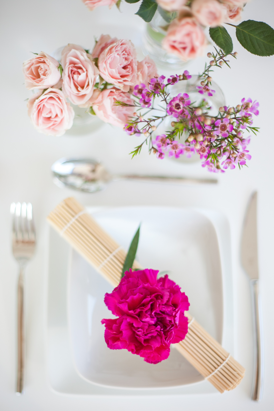 Close-up of a styled place setting with blooms and glassware